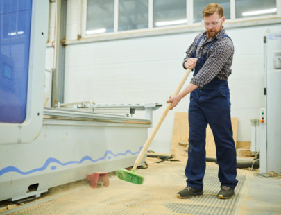man-sweeping-floor-in-factory