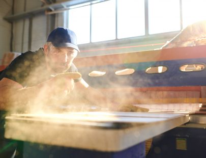 man-using-saw-in-mill-generates-wood-dust
