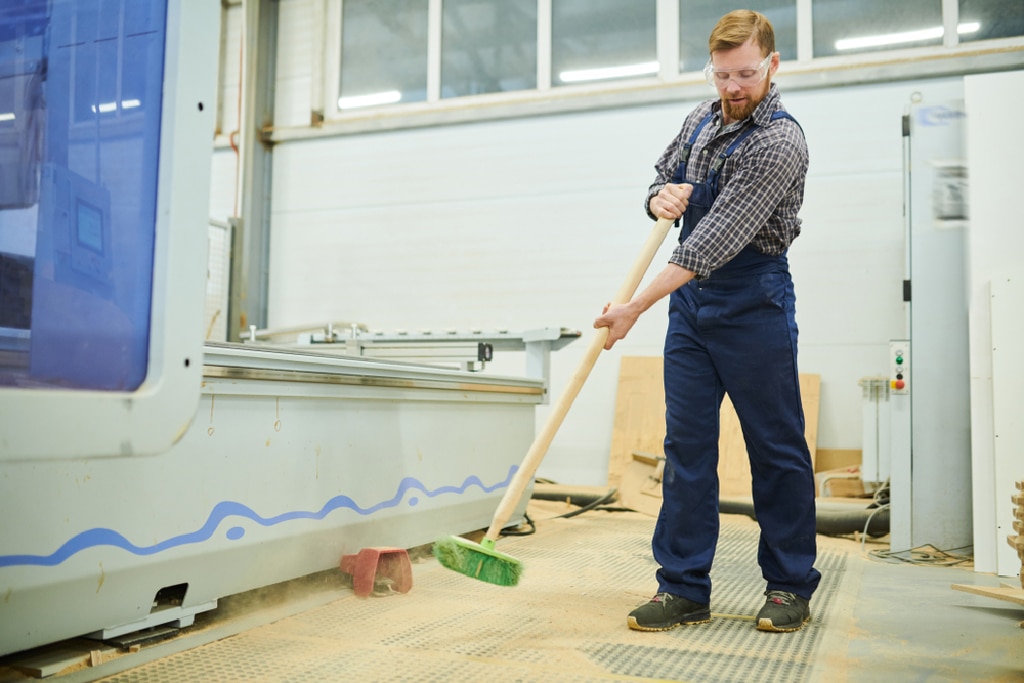 man-sweeping-up-wood-dust-in-mill